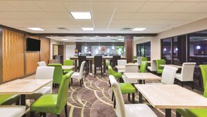 A restaurant with green and white chairs, tables, and a patterned carpet. - La Quinta Inn by Wyndham Austin North (Austin)