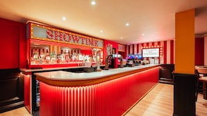 Un bar con decoración a rayas rojas y blancas, un letrero de neón que dice "SHOWTIME" y una barra con diversos botellones.