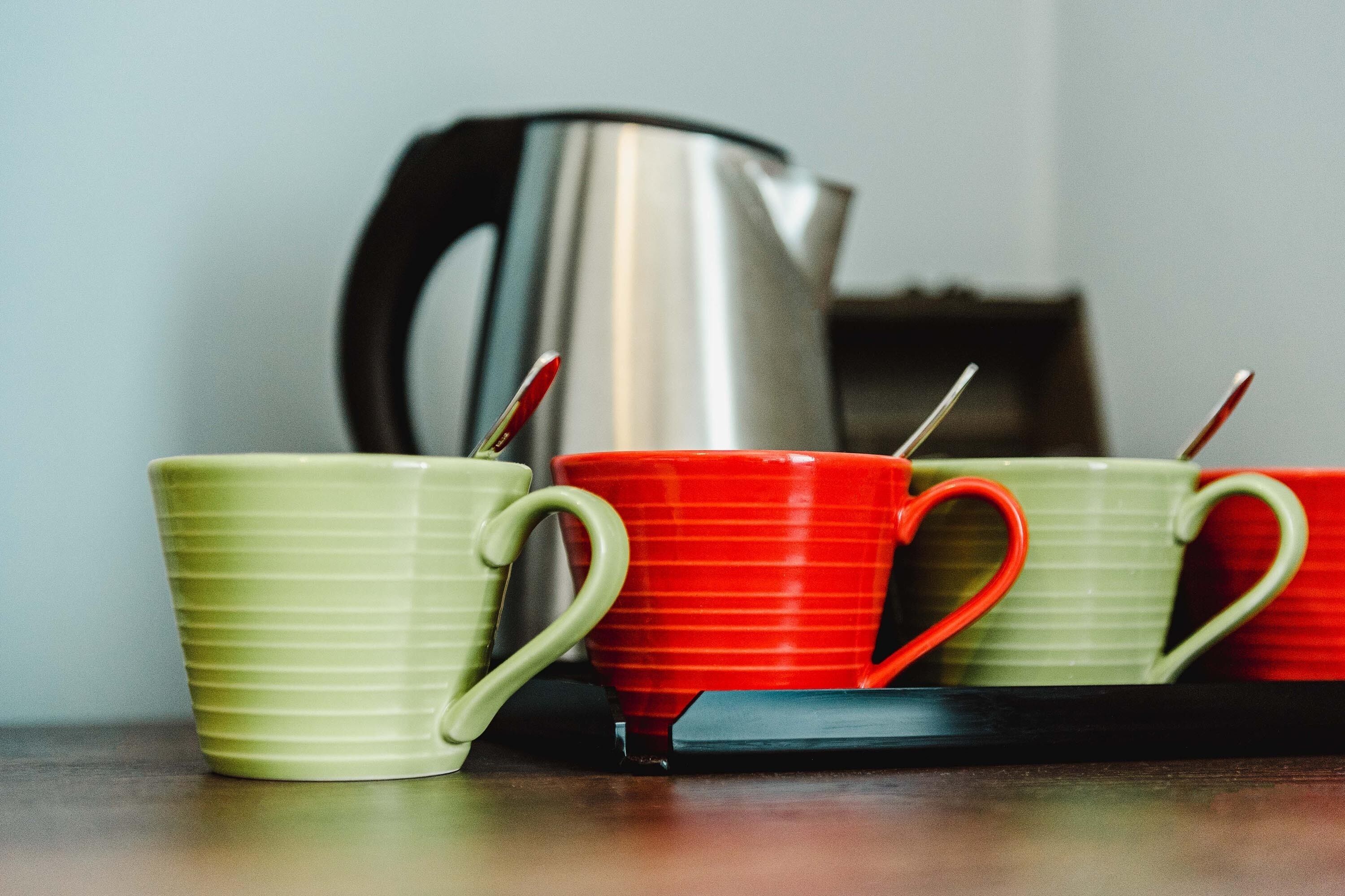 Tres tazas sobre una bandeja, con una tetera al fondo.