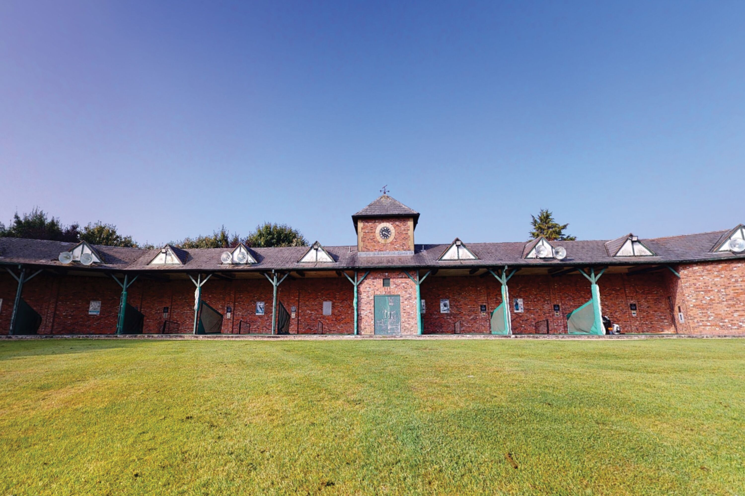 A brick building with a central tower and multiple covered sections.