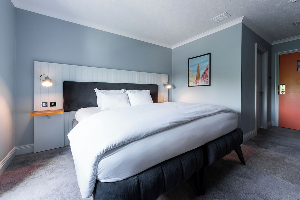 A bedroom with a bed, nightstands, and a painting on the wall.