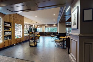 Een ruim café met een houten toonbank, een zithoek en een groot raam met uitzicht op de stad.