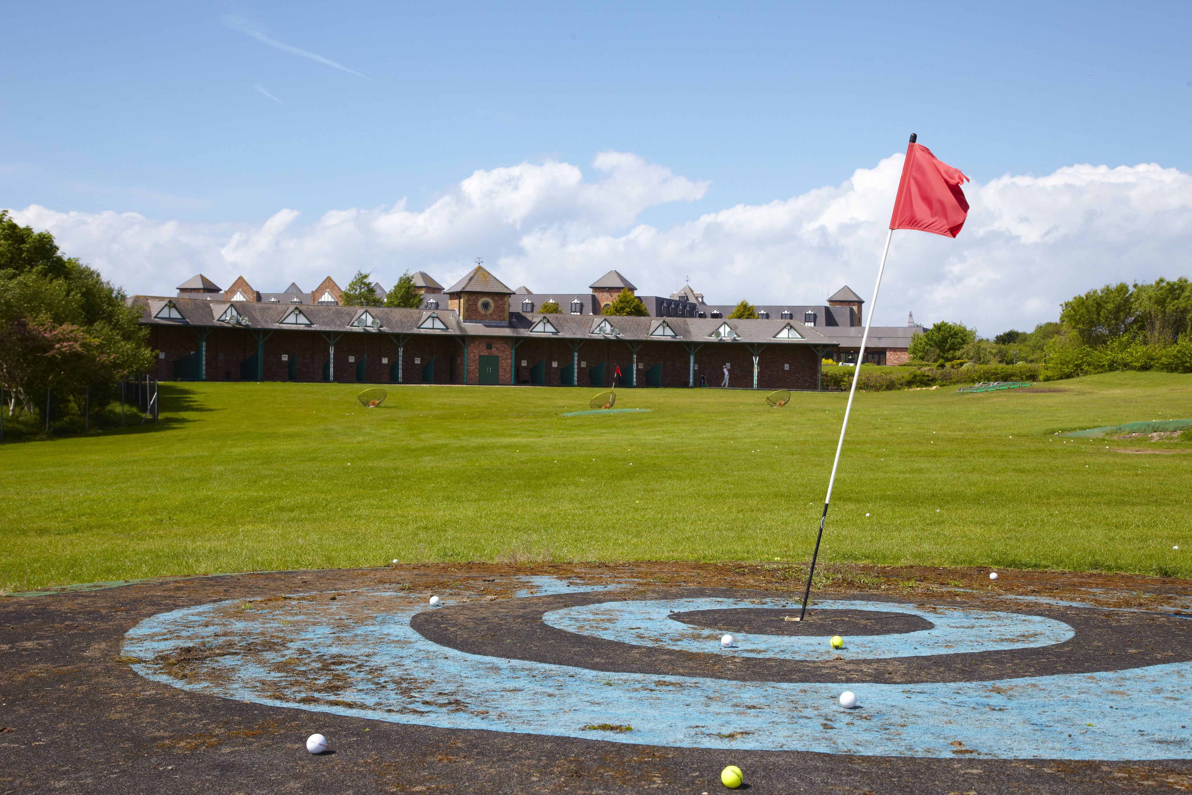 Ein Golfplatz mit einem Clubhaus im Hintergrund.