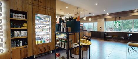 A Starbucks store interior with wooden accents, a refrigerated display, seating area, and a view through large windows.
