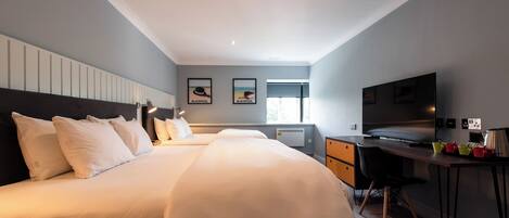A hotel room with a large bed, a desk with a chair, a television, and a window.