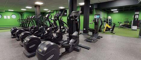 A gym with various exercise equipment, including treadmills and weight machines, arranged in rows.