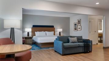 Una habitación de hotel con cama, sofá, mesa y lámpara.