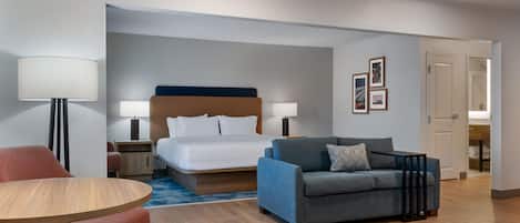 Une chambre d’hôtel avec un lit, un canapé, une table et une lampe.