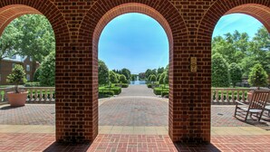 A brick archway leading to a courtyard with a pathway, benches, and a sign indicating WiFi availability. - The Founders Inn and Spa, Tapestry Collection by Hilton (Virginia Beach)