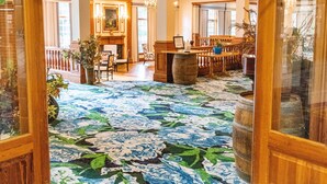 A grand entrance with a floral carpet leading to a seating area and a fireplace. - The Founders Inn and Spa, Tapestry Collection by Hilton (Virginia Beach)