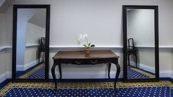 Una habitación con alfombra de diseño azulado, una mesa de madera con una orquídea en maceta y dos espejos a cada lado.