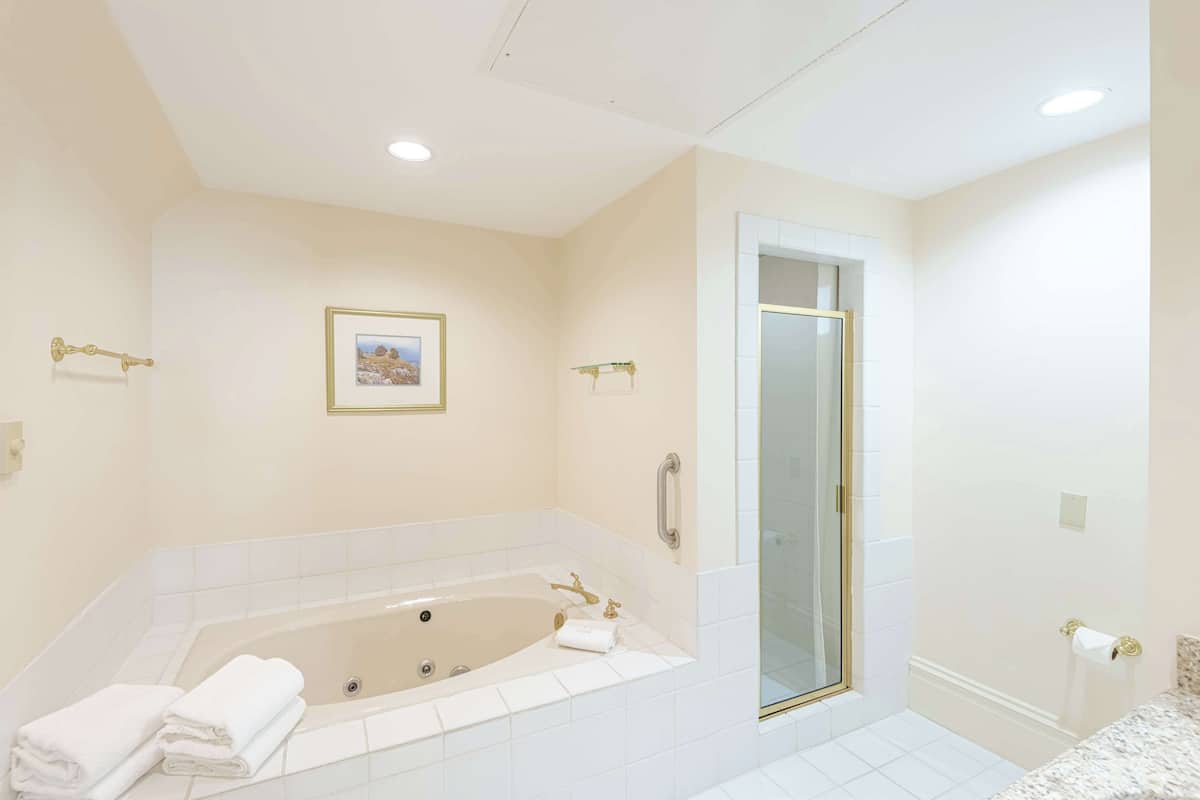 A modern bathroom with a large bathtub, a glass shower enclosure, and a framed picture on the wall.