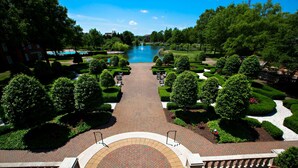 A landscaped pathway leading to a lake with manicured trees and a brick walkway. - The Founders Inn and Spa, Tapestry Collection by Hilton (Virginia Beach)