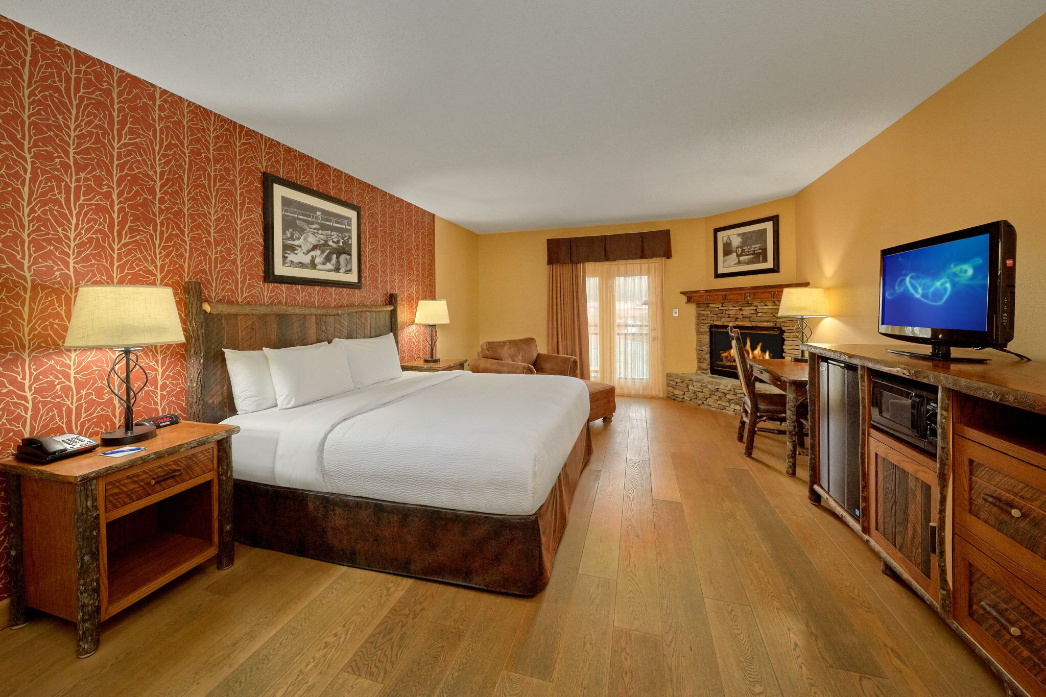 A hotel room with a large bed, wooden nightstands, a television, and a dining area with a table and chairs.
