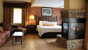Een knus hotelkamer met een bed, een bank, een kleine tafel, een lamp en een open haard.
