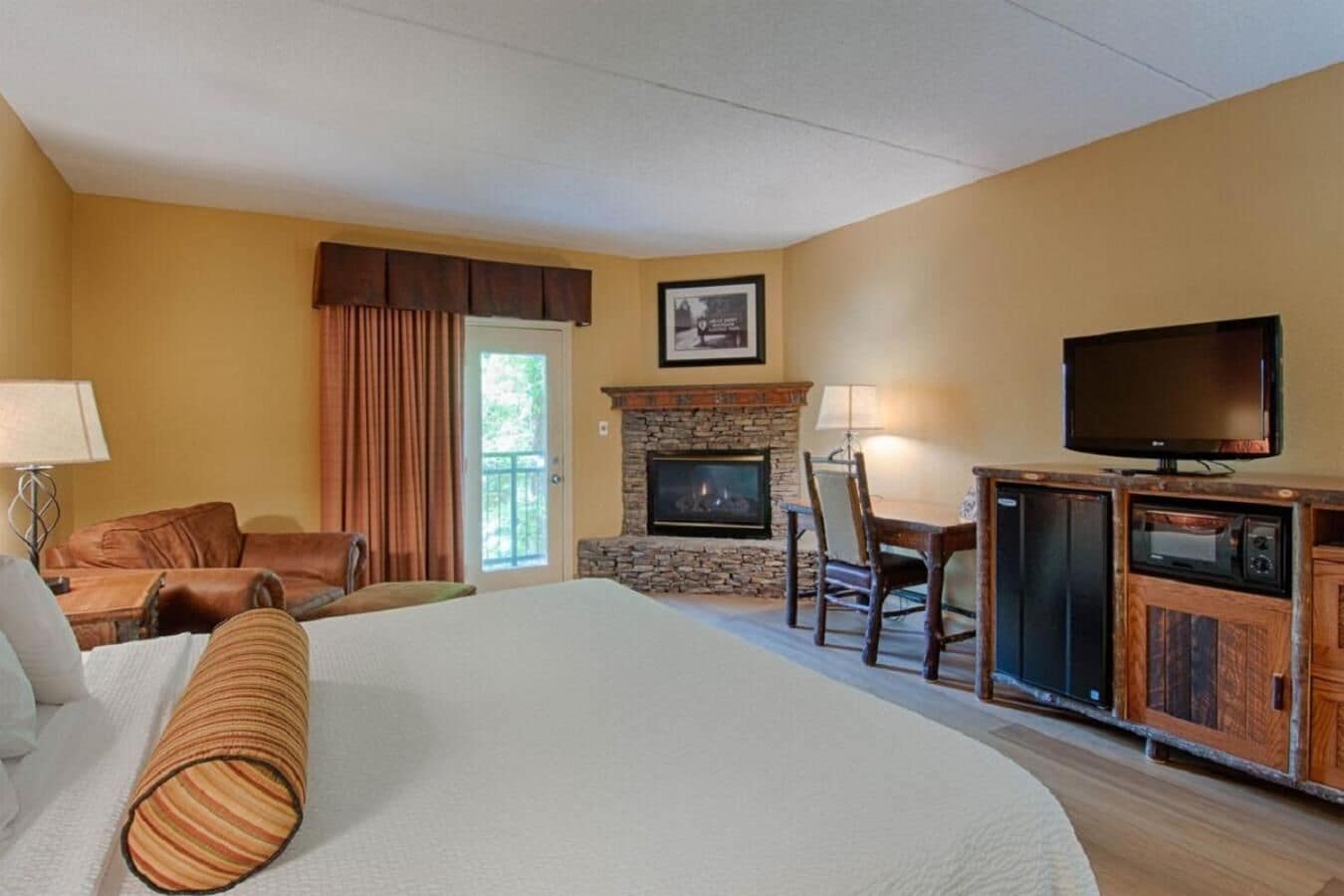 Een hotelkamer met een groot bed, een stenen openhaard, een televisie en een zithoek met stoelen.