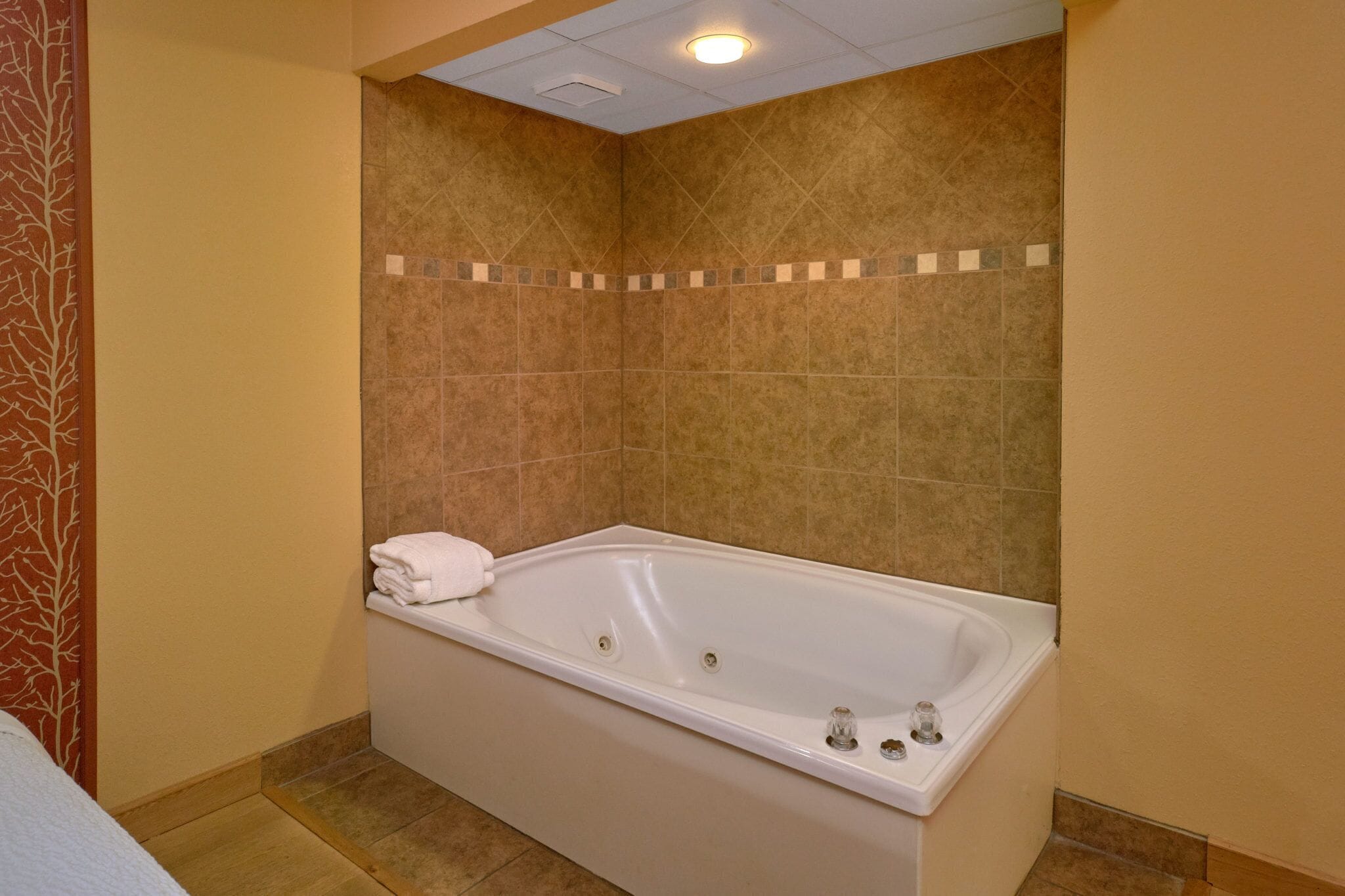 Un baño con una bañera grande, paredes color beige y una zona de ducha con azulejos.