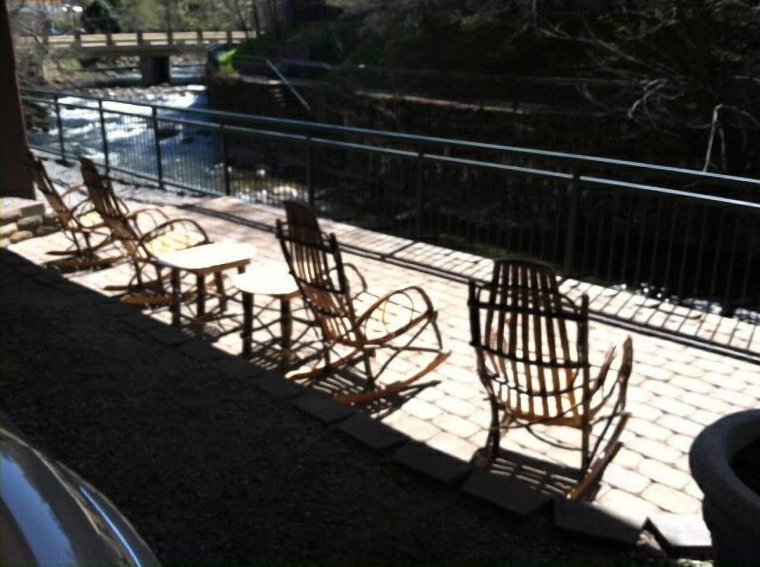 A patio with outdoor seating, a railing, and a view of a river.