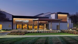 Um hotel Courtyard by Marriott com design moderno, janelas amplas e um gramado bem cuidado.