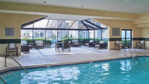 Uma área de piscina com assentos e um terraço envidraçado.