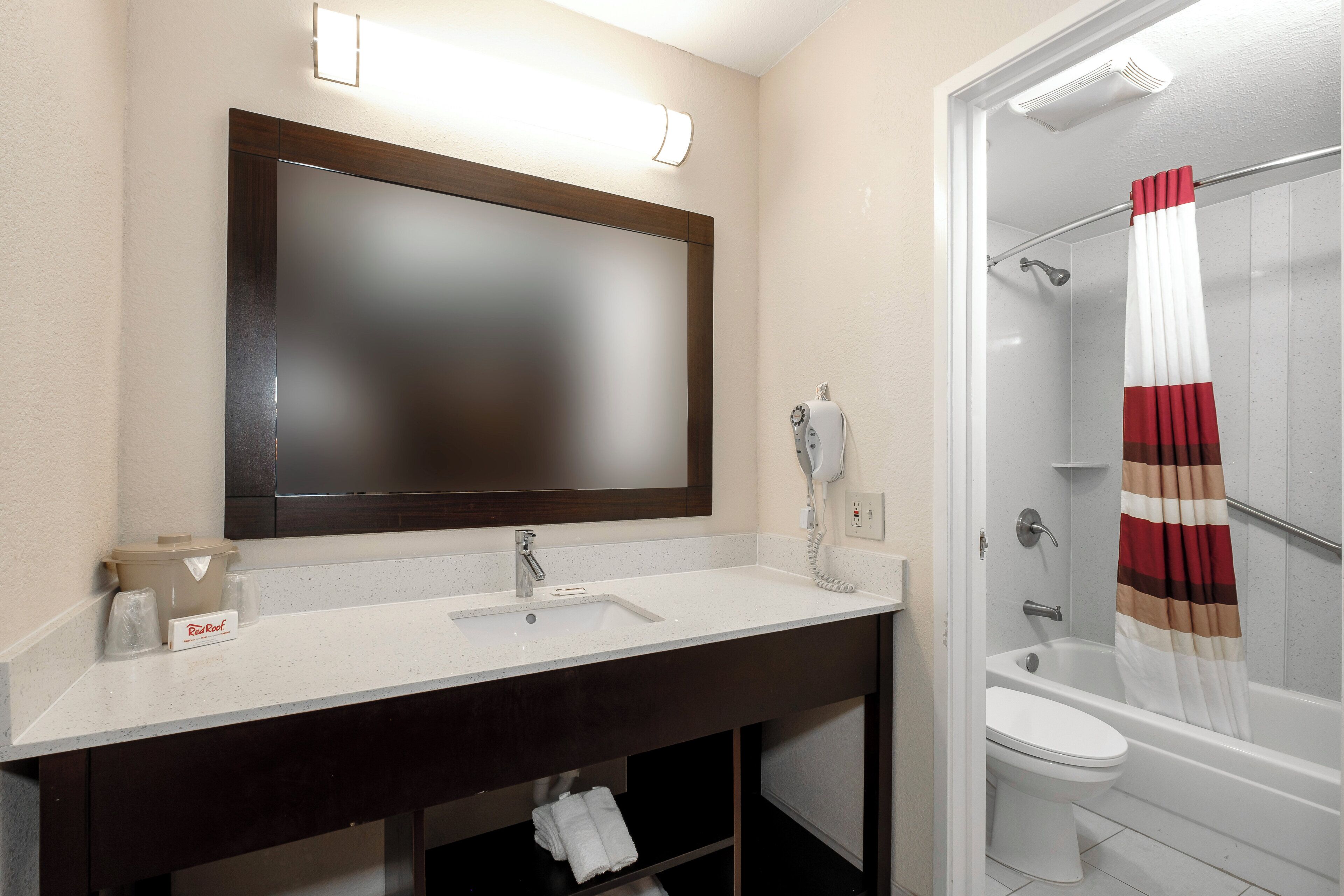A bathroom with a large mirror, a sink, a toilet, and a shower.