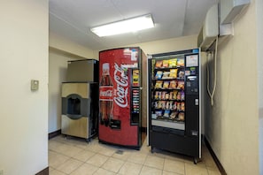A vending machine and a Coca-Cola refrigerator in a room with tiled flooring and a fluorescent light overhead. - Red Roof Inn Tallahassee - University (Tallahassee)