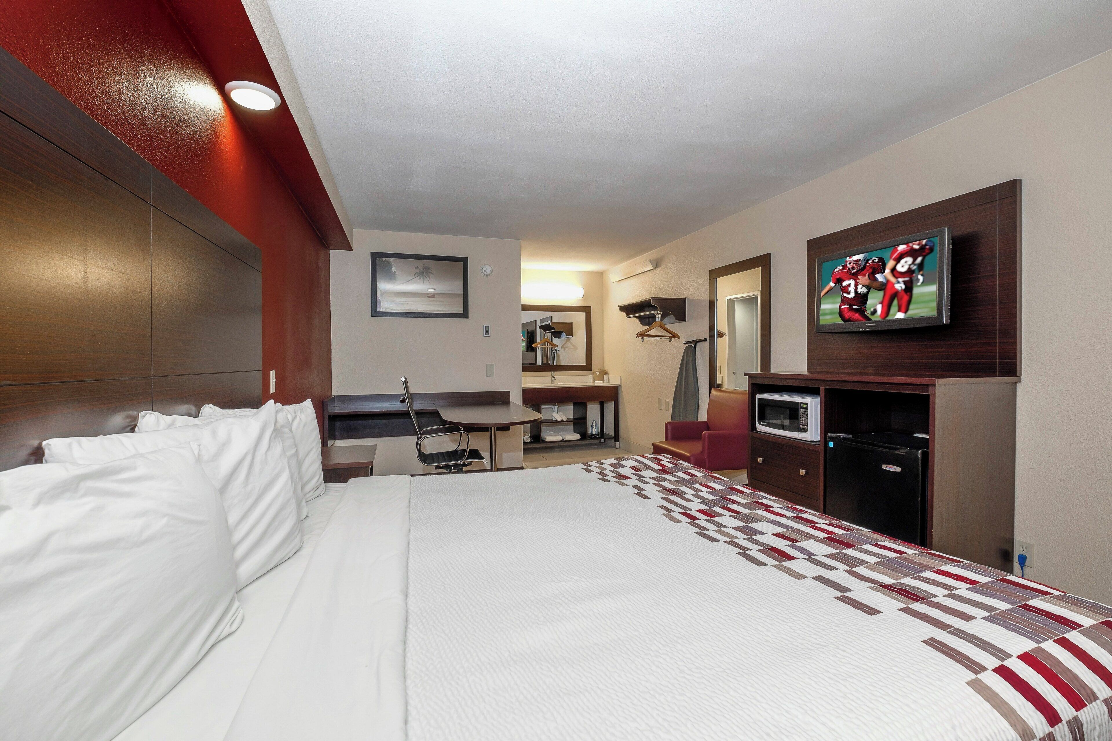 Une chambre d’hôtel avec un grand lit, un bureau, une télévision et un four à micro-ondes.