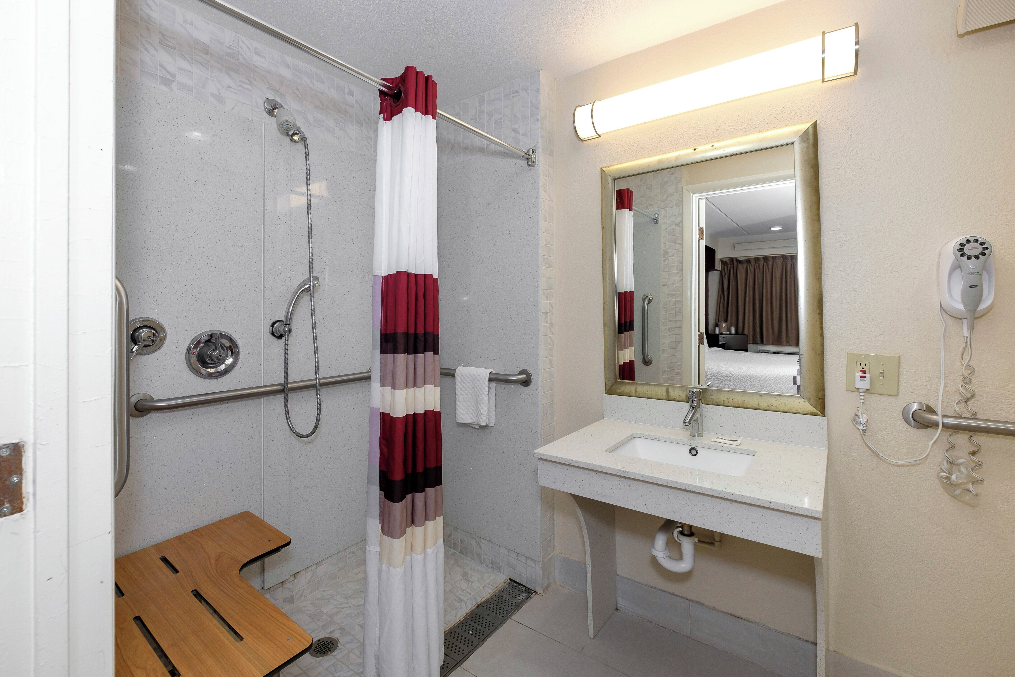 Ein Badezimmer mit Dusche, Waschbecken, Spiegel und Fön.