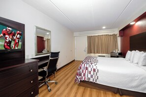 Une chambre d’hôtel équipée d’un lit, d’un bureau, d’une chaise, d’une télévision et d’un miroir.
