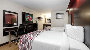 A hotel room with two beds, a TV, a desk with a chair, and a mirror.