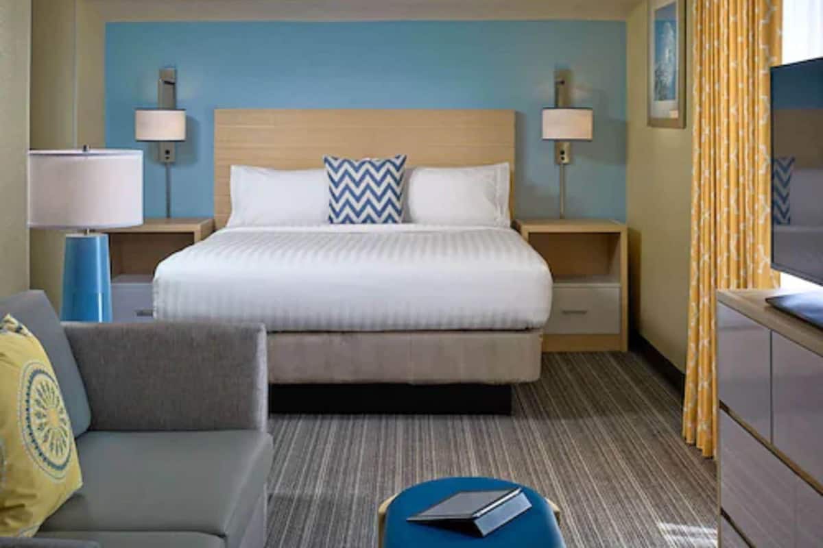 Une chambre d’hôtel comprenant un lit, des tables de chevet, un bureau, une chaise et une lampe.