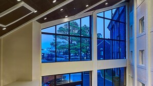 A spacious lobby with large windows, a reception desk, seating area, and a view of the street. - Sonesta Simply Suites Memphis East Poplar Pike ​ (Memphis)