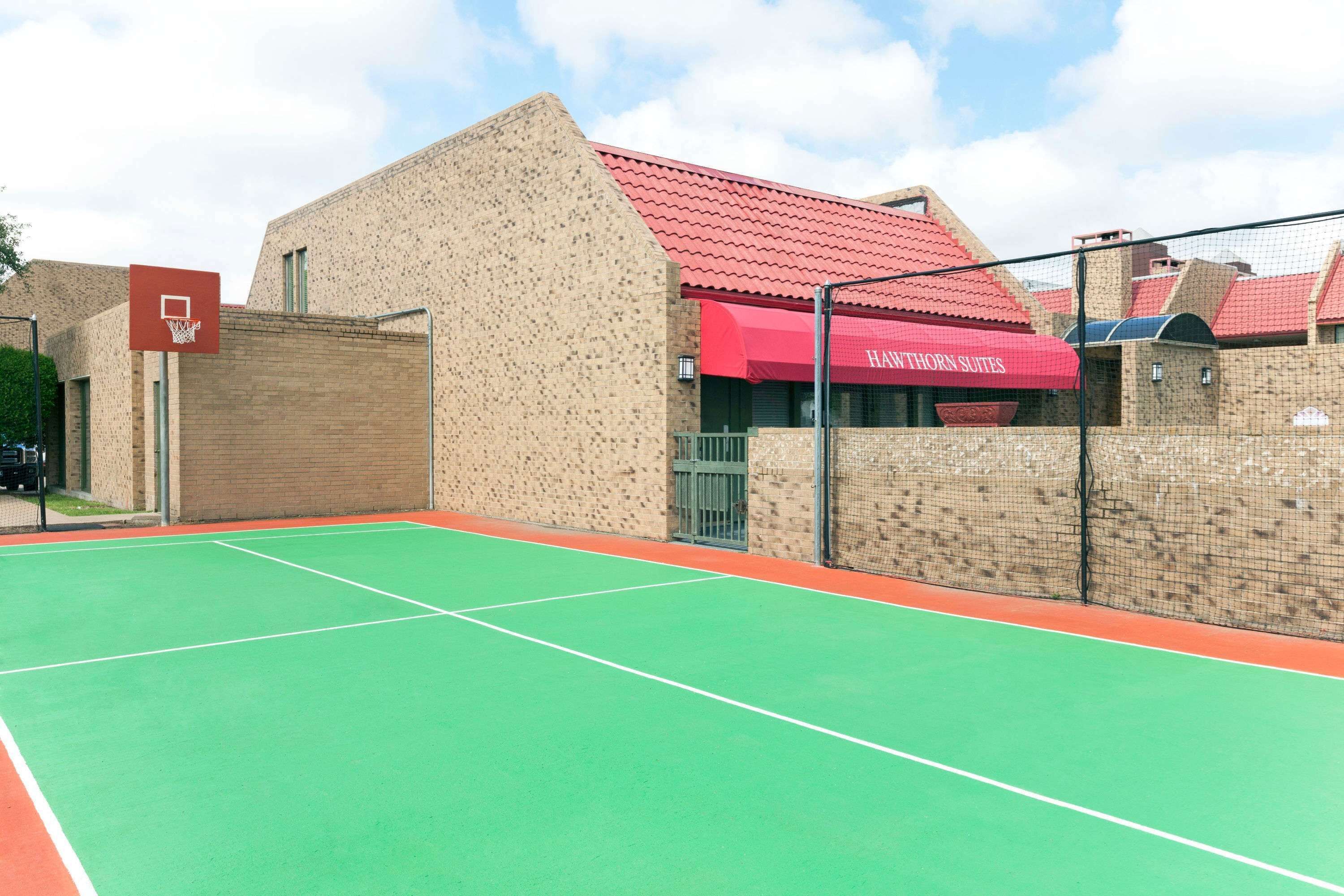 An outdoor tennis court adjacent to a building with a red awning labeled "Havethorn Suites."