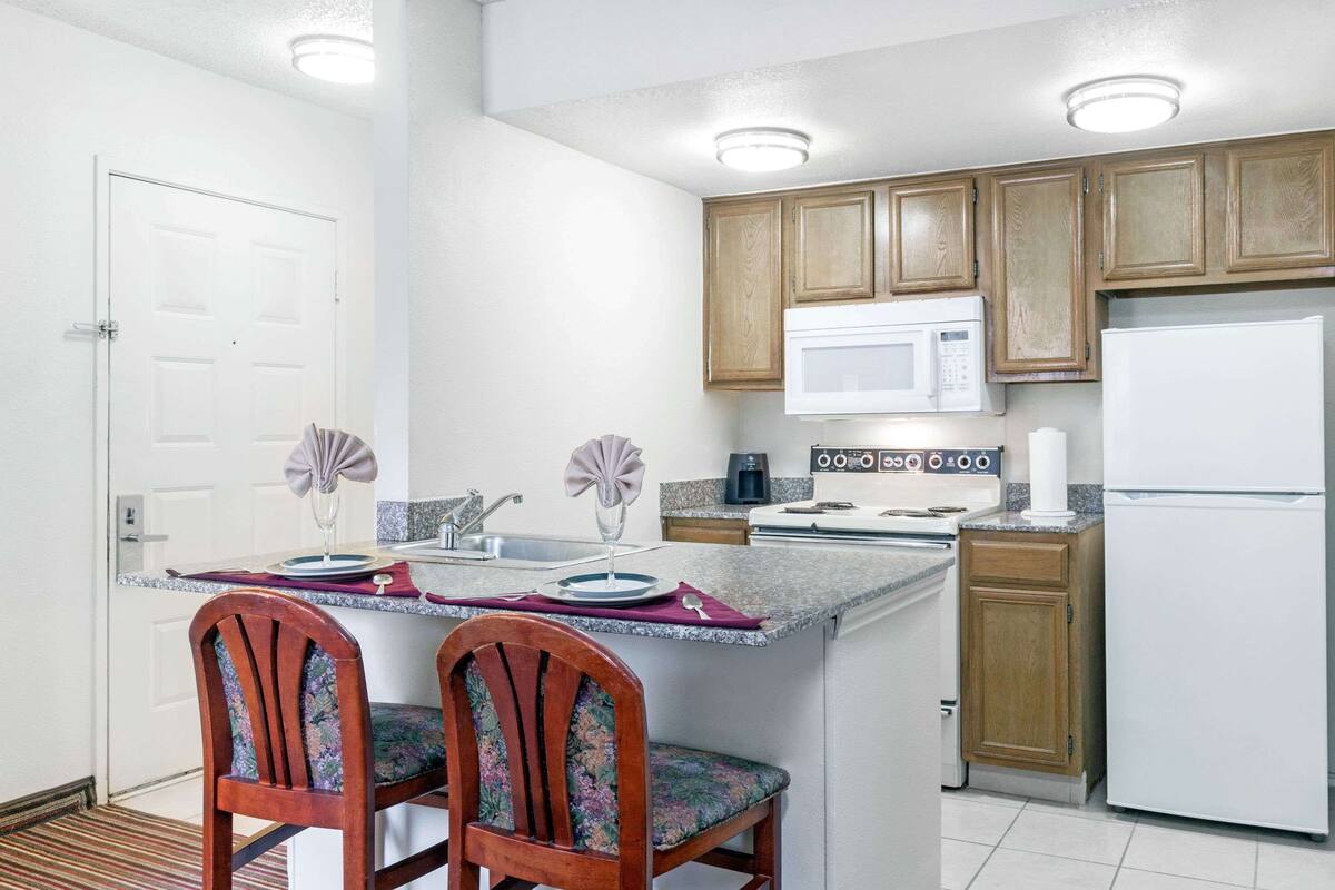 A compact kitchen with a central island, wooden cabinets, a microwave, a stove, and a refrigerator.