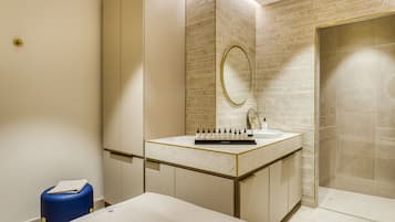 A modern bathroom with a marble vanity, a large mirror, and a shower area.