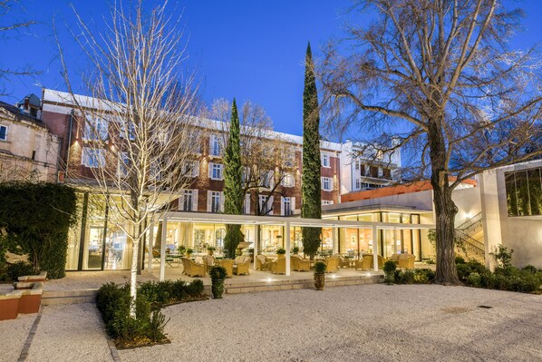Stroll through the serene courtyard, surrounded by traditional and modern architecture, featuring a glass lobby and beautifully maintained outdoor seating.