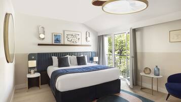 A modern hotel room with a large bed, a small side table, a chair, a balcony with a view, and a ceiling light fixture.