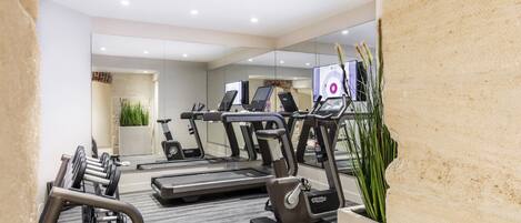 A modern gym with treadmills, elliptical machines, and free weights.