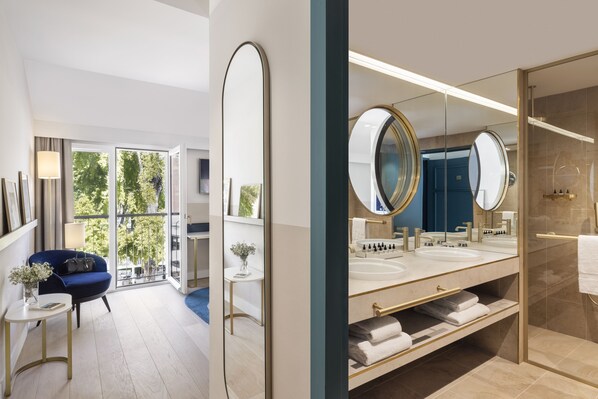A modern bathroom with a large mirror, dual sinks, and a glass shower enclosure.