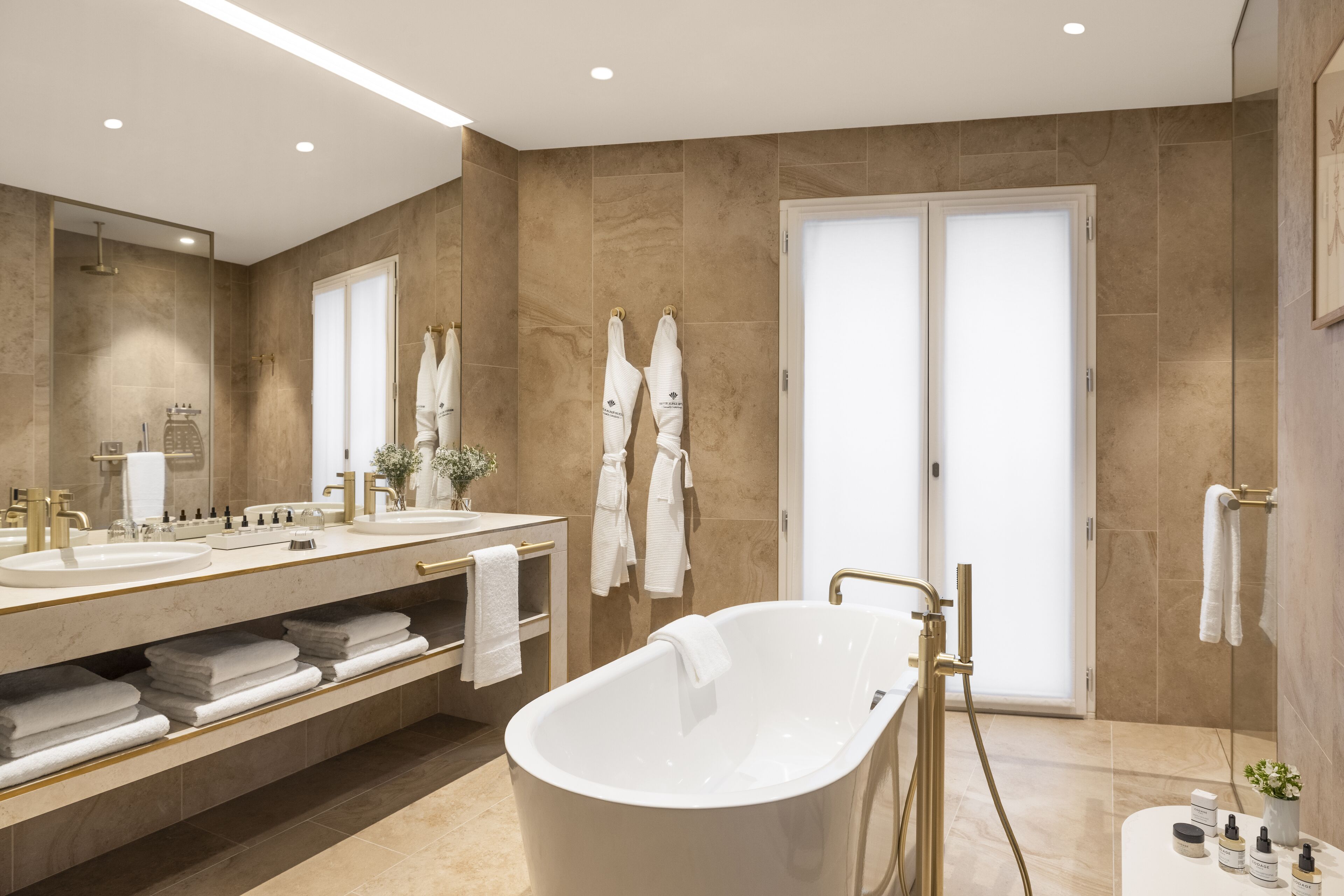 Ein modernes Badezimmer mit einer freistehenden Badewanne, zwei Waschbecken und einem großen Spiegel.