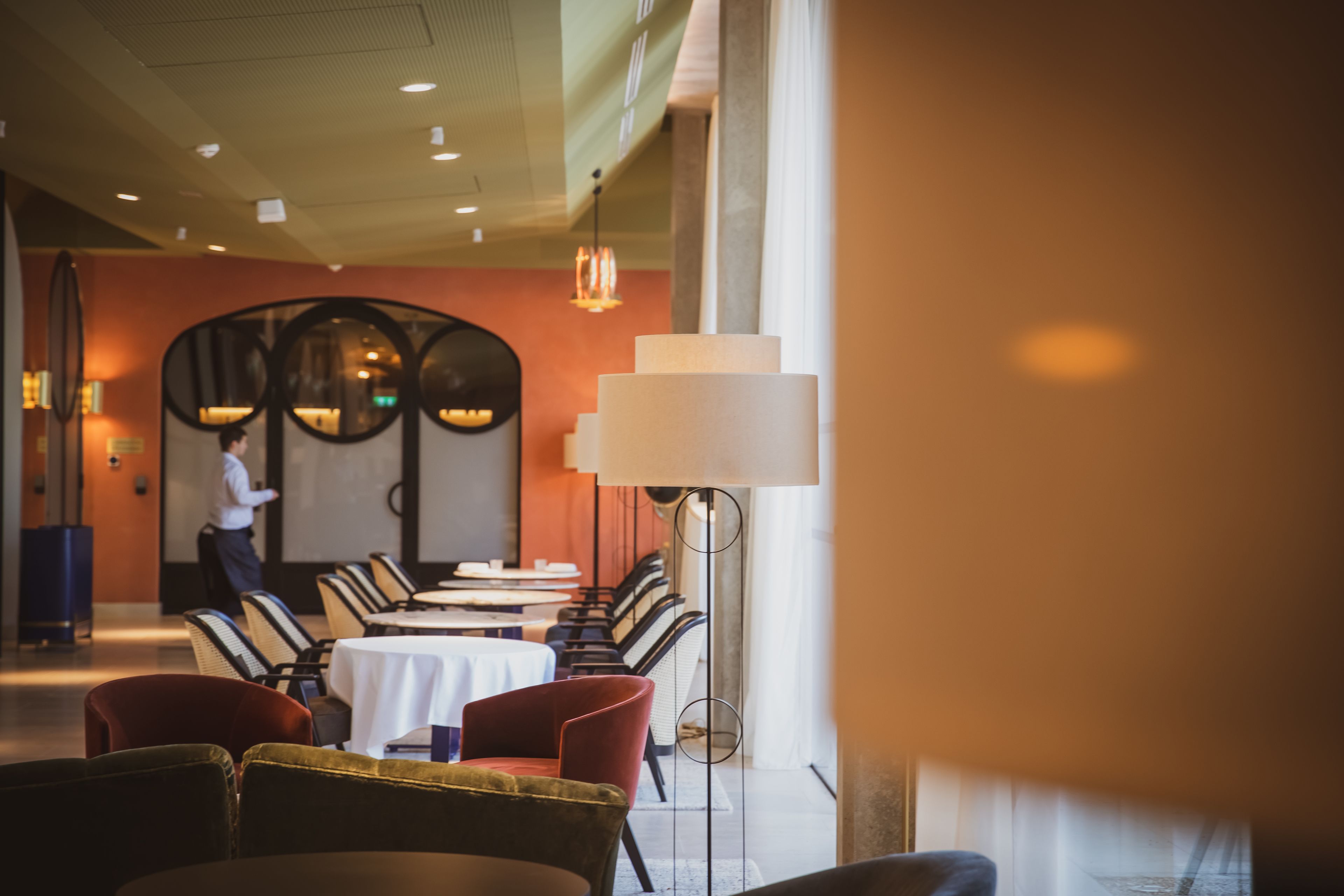 Un restaurante con una mesa larga, sillas y un camarero.