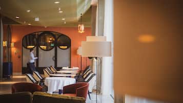 Un restaurante con una mesa larga, sillas y un camarero.