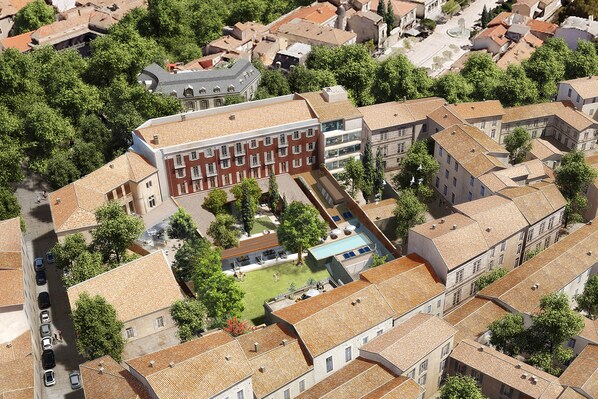 An aerial view of a building complex with multiple buildings, a swimming pool, and surrounding greenery.