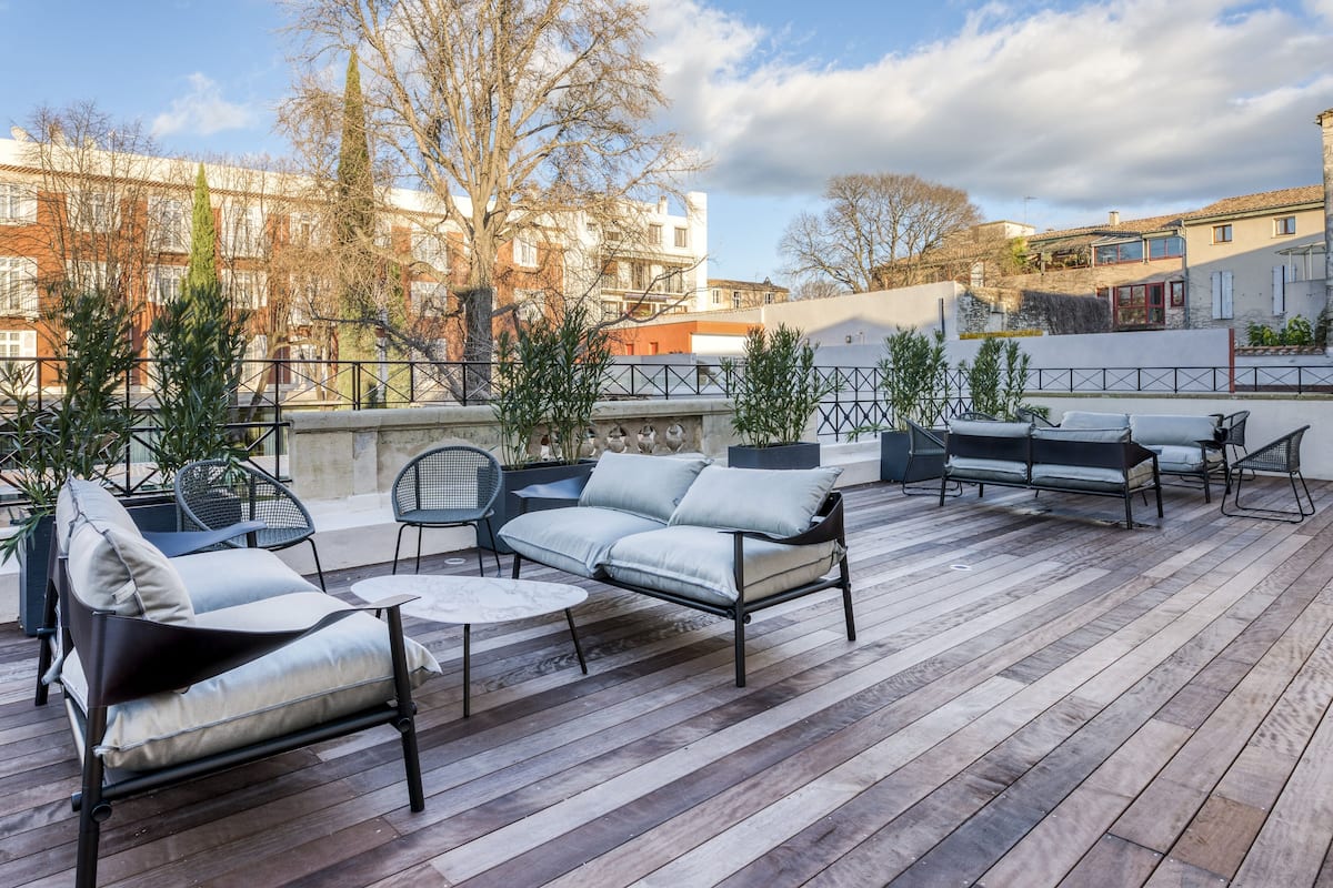 An outdoor patio with a wooden deck, a sofa, chairs, and a small table.