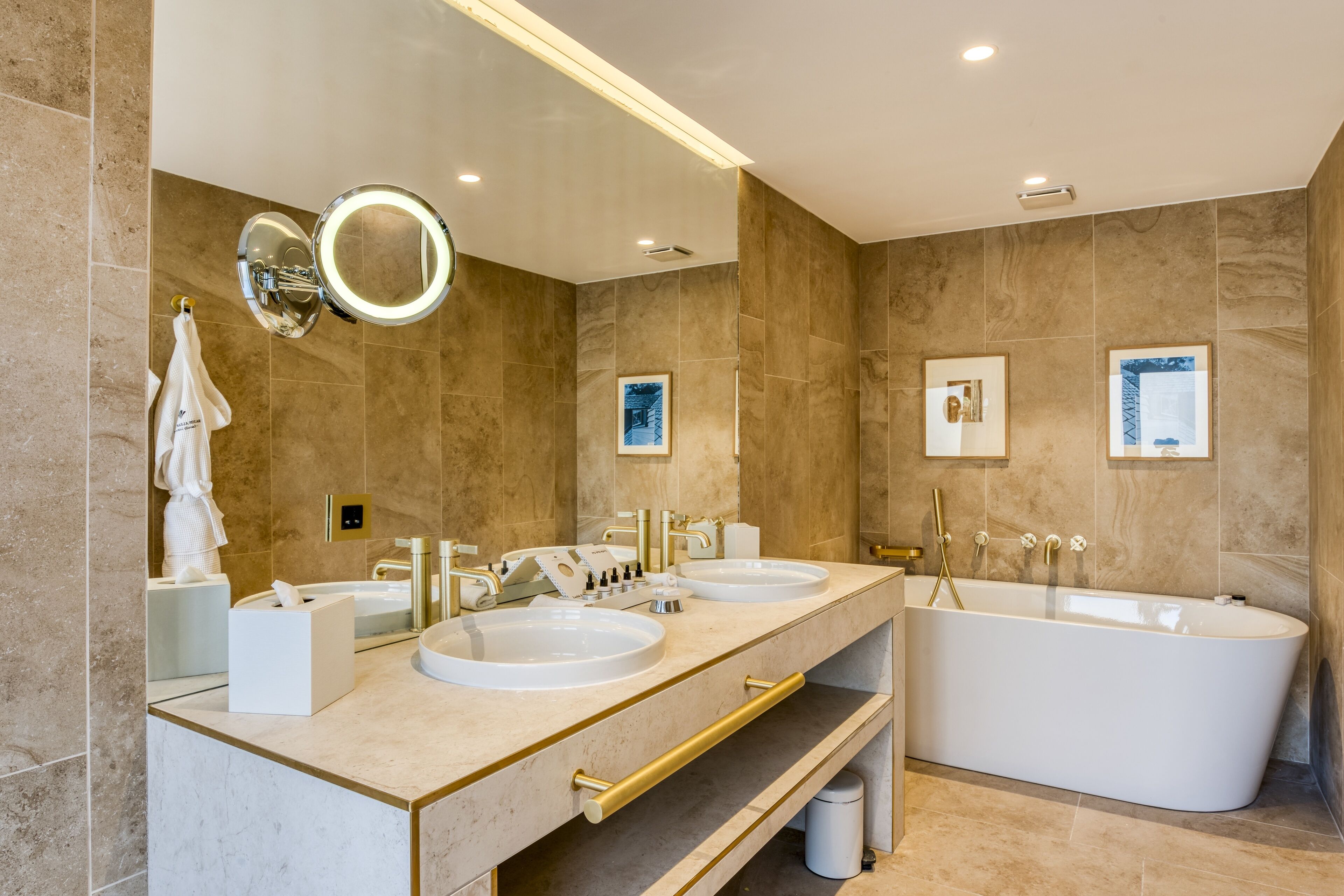 Un baño moderno con dos lavamanos, una bañera grande y un tocador con espejo.