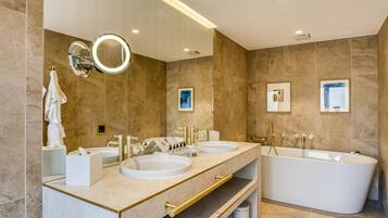 Un baño moderno con dos lavamanos, una bañera grande y un tocador con espejo.