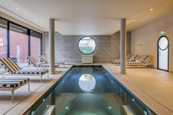 Una piscina techada, una piscina al aire libre, sombrillas