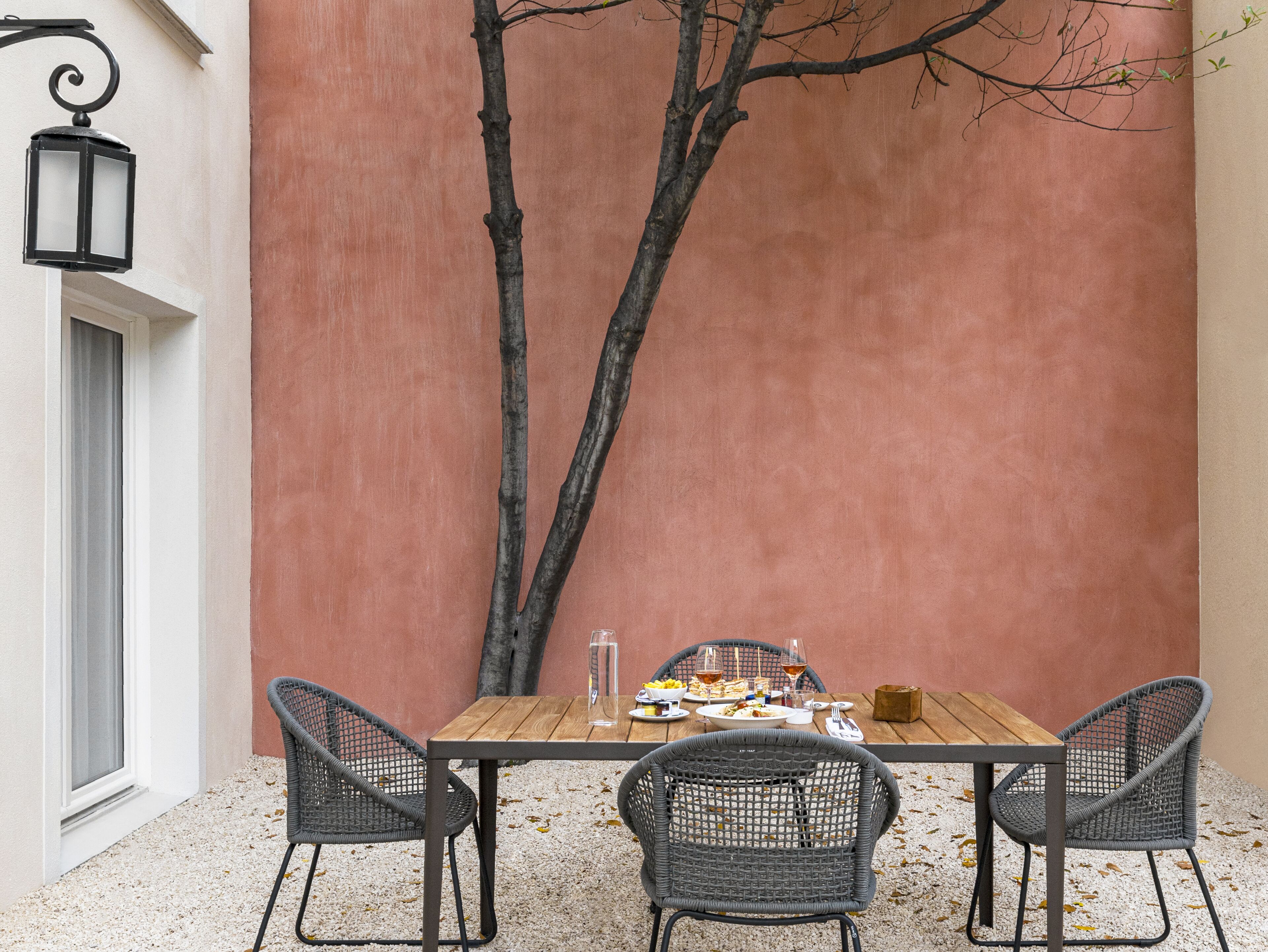 A wooden table with chairs, a glass of water, and plates of food.