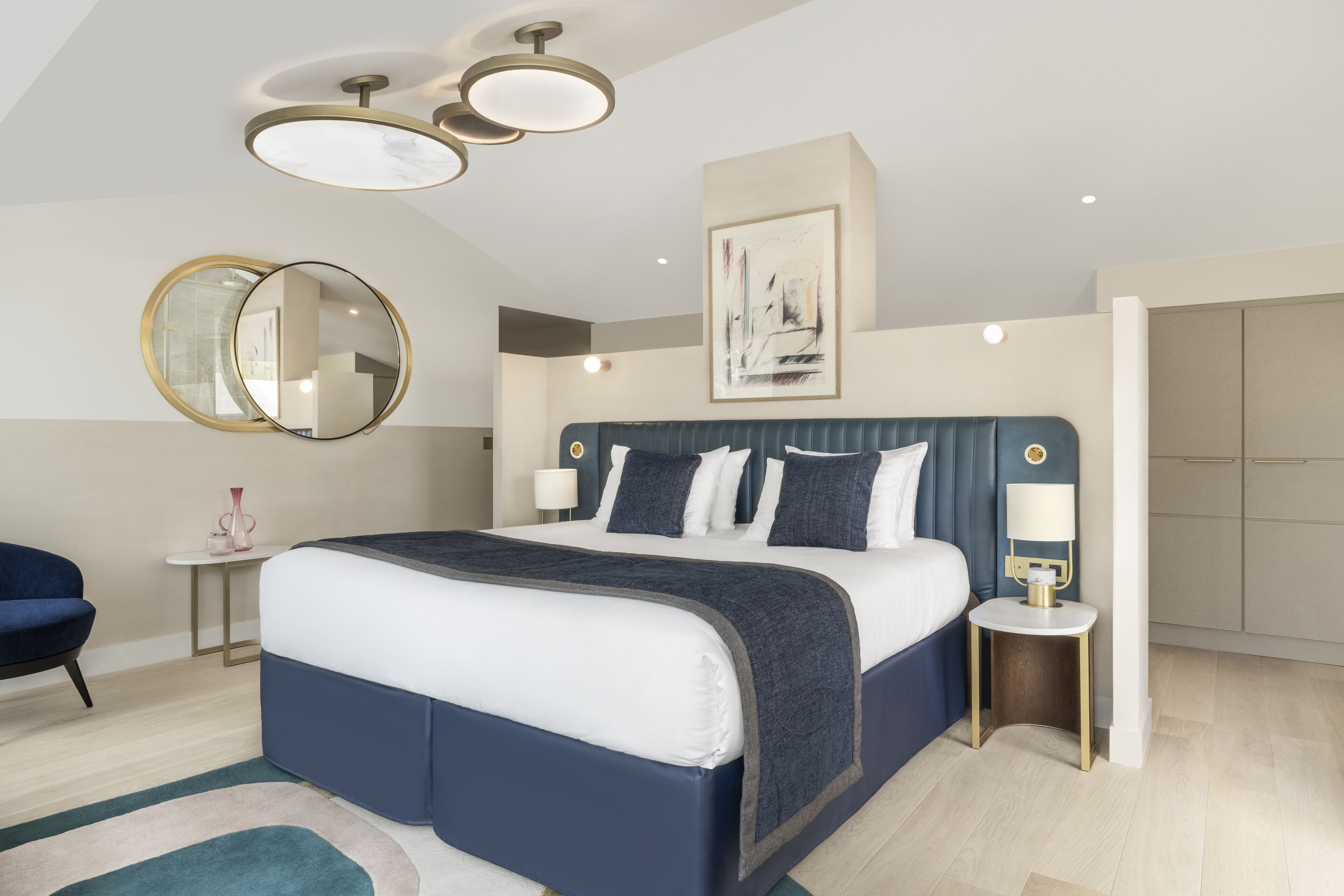Un dormitorio moderno con una cama grande, mesitas de noche, una silla y un espejo.