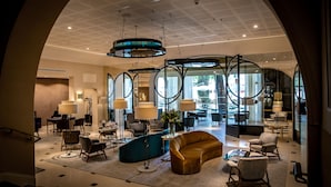 A spacious lobby with modern furniture, large windows, and a unique ceiling design.